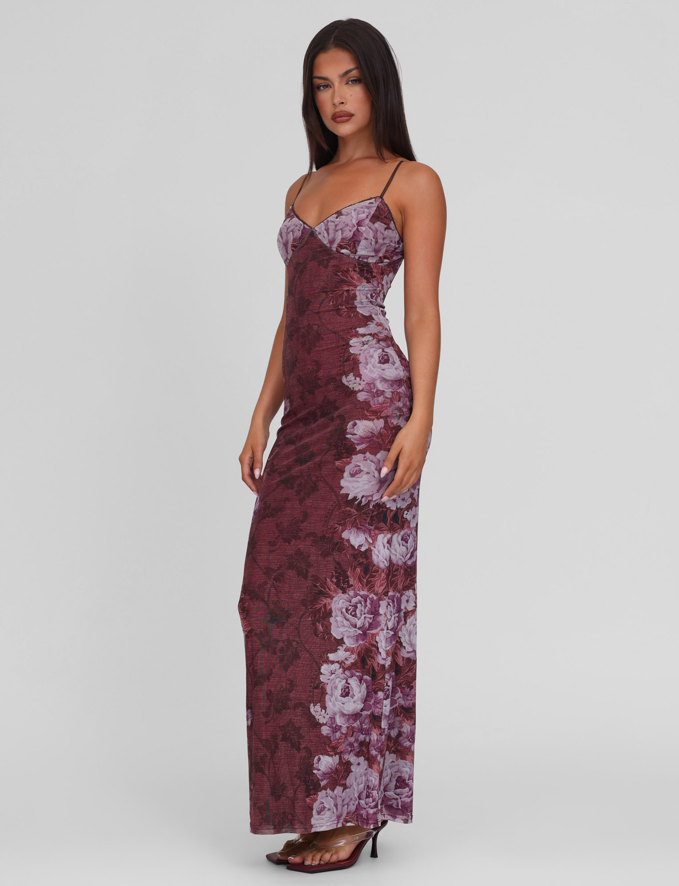 A woman models the TIGERMIST JULIANNA DRESS - MULTI: FLORAL: ROSE STRIPE, a sleeveless, floor-length gown with thin straps and a floral rose stripe print, styled with black high-heeled sandals against a plain white background.