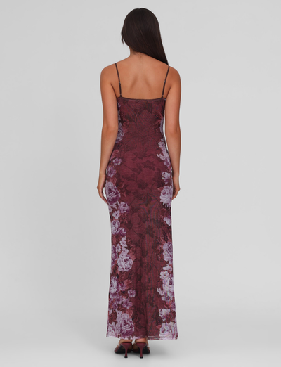 A woman with long dark hair models the TIGERMIST JULIANNA DRESS - MULTI : FLORAL : ROSE STRIPE, a sleeveless maxi dress with a floral stripe print, standing with her back to the camera against a plain light gray background.